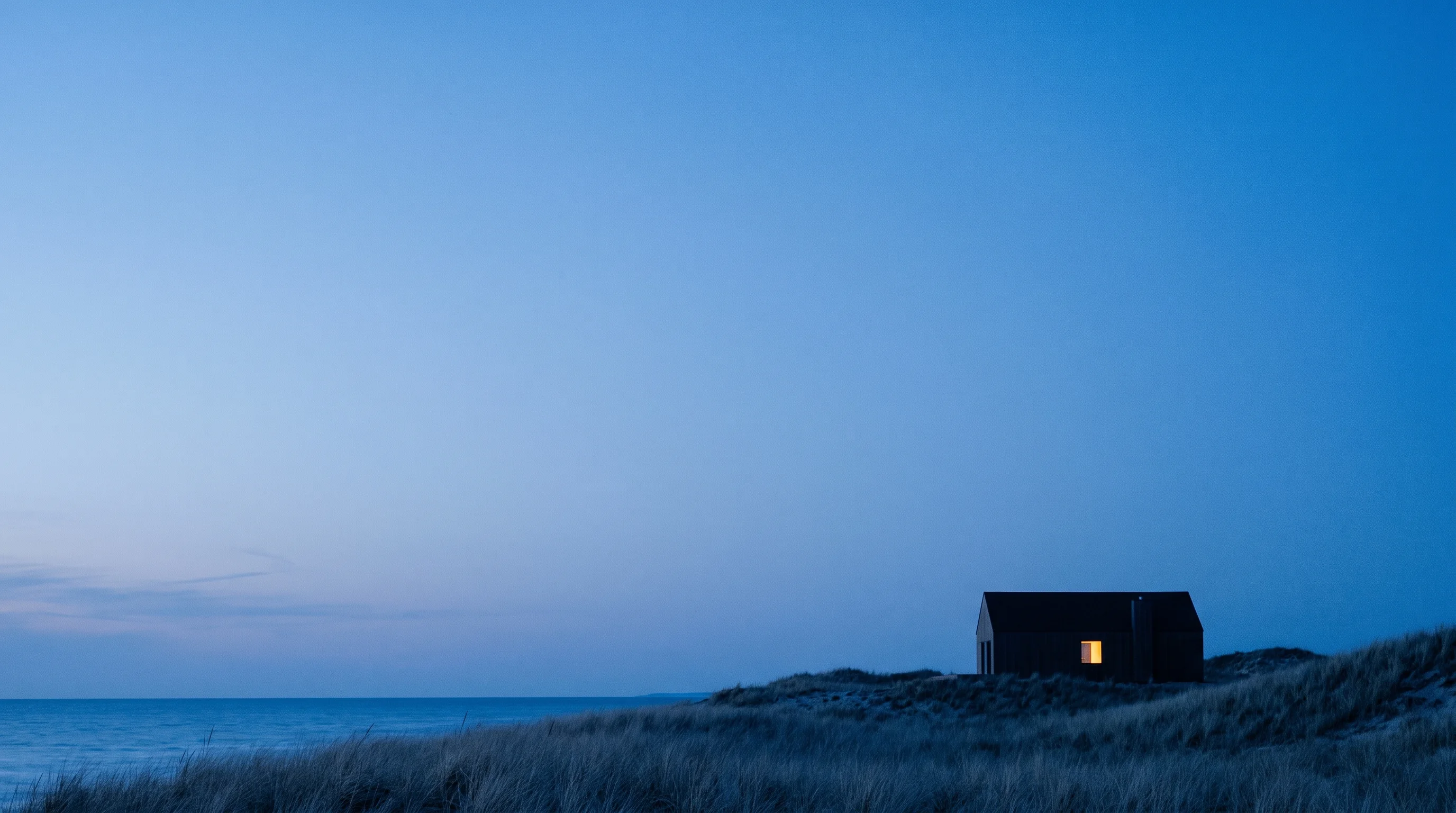 A distant house on a Lake Michigan dune ridge at blue hour